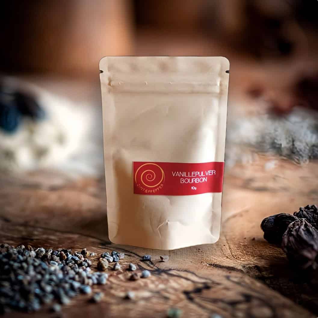 Bourbon Vanille Pulver aus Madagaskar – 100 % natürlich. Eine 10 g Tüte Bourbon Vanille Pulver auf einem Olivenholzbrett.