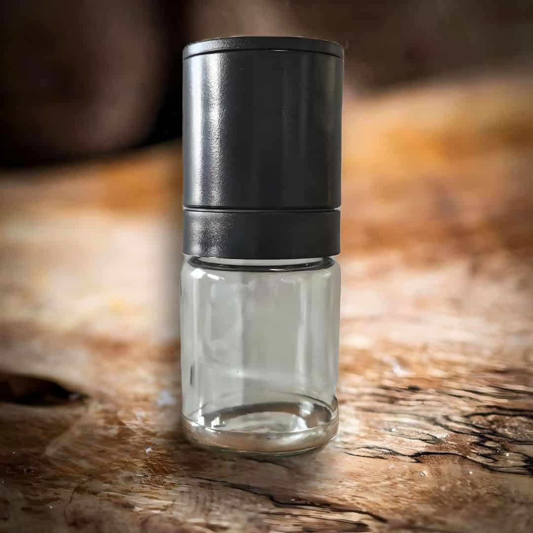 Eine 80 ml Pfeffermühle mit einem Keramikmahlwerk und einem Kunststoffverschluß auf einem Olivenholzbrett.