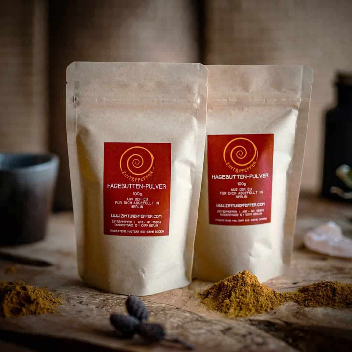 Zwei Zip-Tüten auf einem Olivenholzbrett. Bei dem Produkt handelt es sich um Hagebutte, mit einer Füllmenge von 100g.