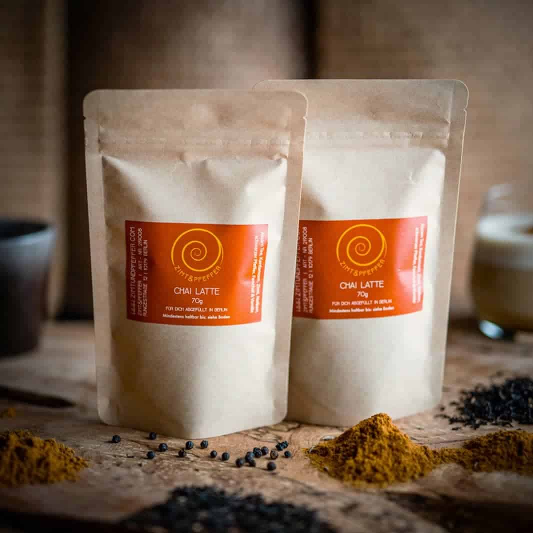 Zwei Tüten mit je 70g Chai Latte Gewürzmischung auf einem Olivenholzbrett