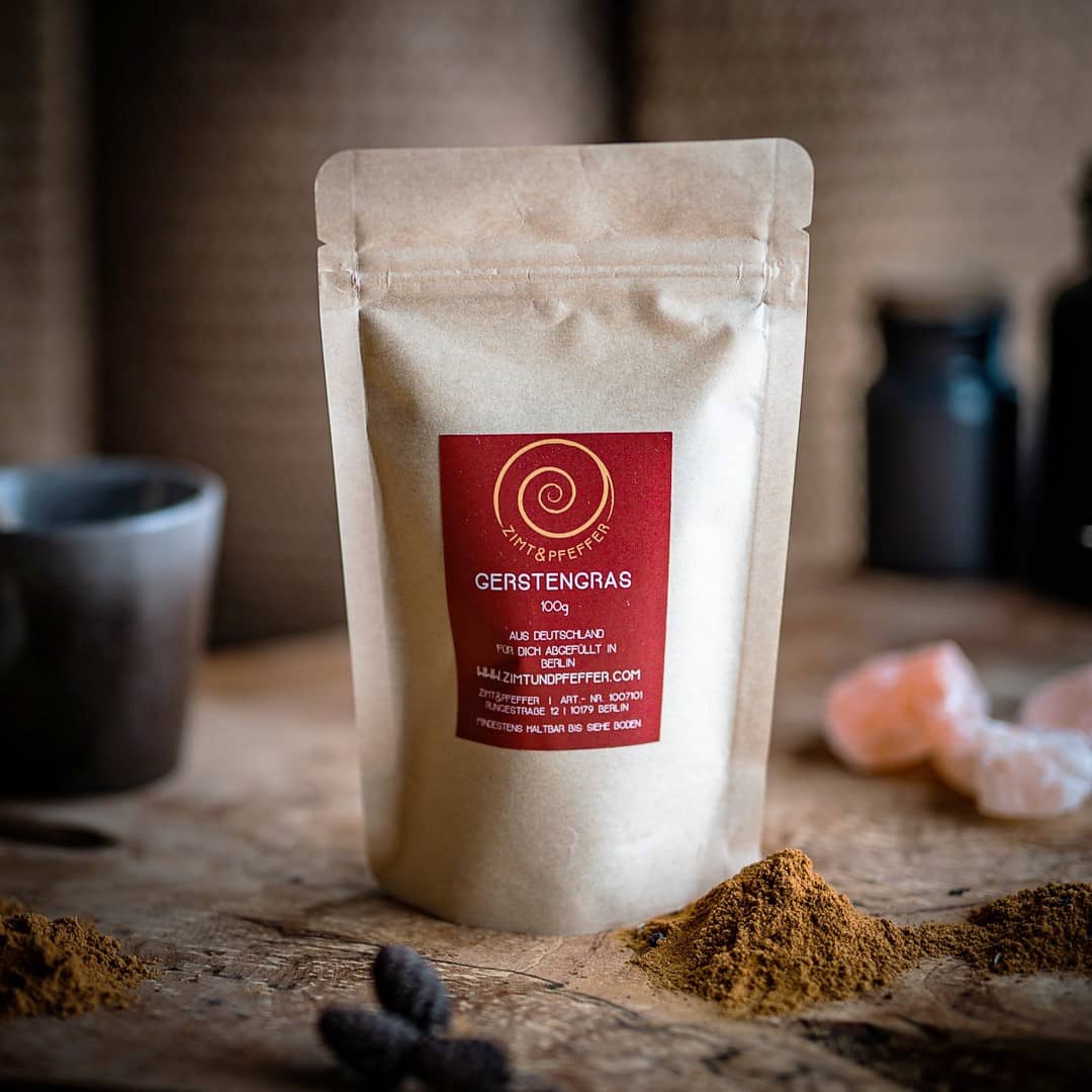 Gerstengras Pulver von Zimt&Pfeffer in einer Tüte auf einem Olivenholzbrett