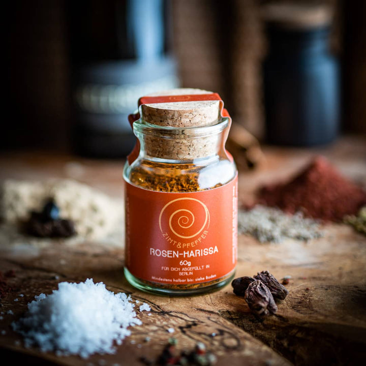Ein Glas 60g Rosen-Harissa auf einem Olivenholzbrett.