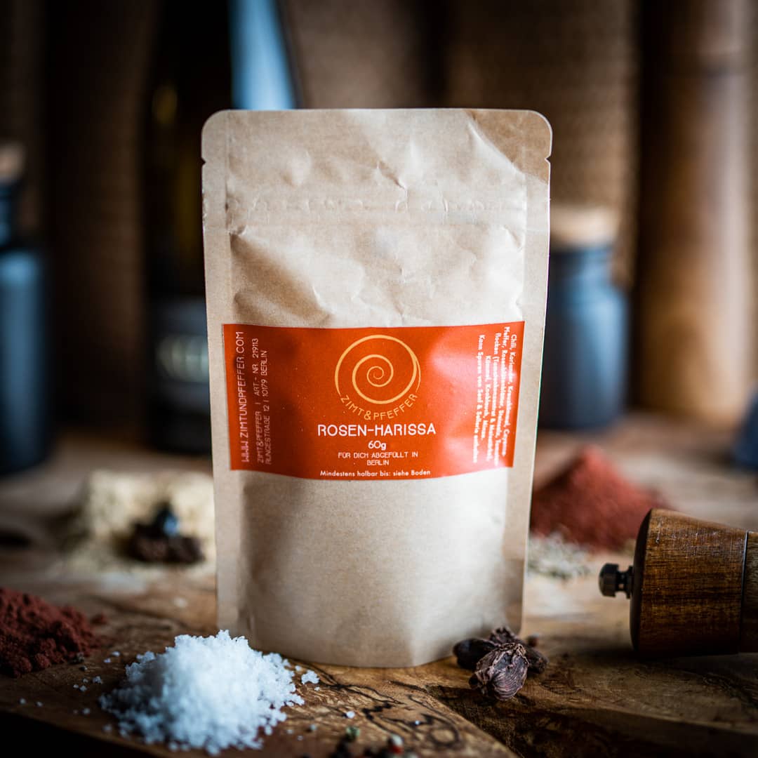 Eine 60g Tüte Rosen-Harissa auf einem Olivenholzbrett.