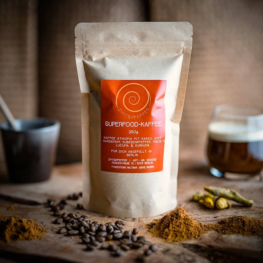 Eine 250g Tüte Superfoodkaffee auf einem Olivenholzbrett. Eine Mischung aus äthiopischen Kaffee, Rohkakao, Zimt, Kardamom, Kubebenpfeffer, Maca, Lucuma und Kurkuma.