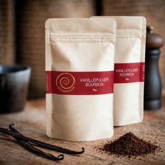 Bourbon Vanille Pulver aus Madagaskar – 100 % natürlich. Zwei 10g Tüten Bourbon Vanille Pulver auf einem Olivenholzbrett.