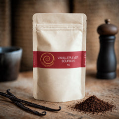 Bourbon Vanille Pulver aus Madagaskar – 100 % natürlich. Eine 10 g Tüte Bourbon Vanille Pulver auf einem Olivenholzbrett.