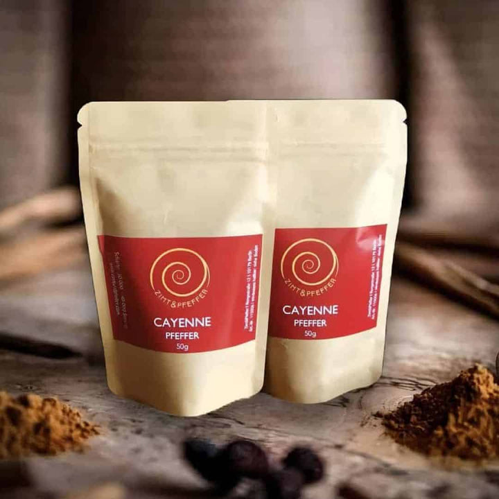 Zwei Tüten Cayenne Pfeffer auf einem Olivenholzbrett.