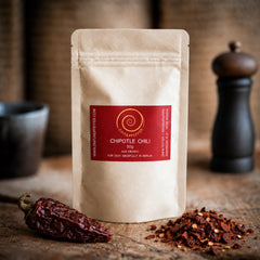 Eine Tüte 50g Chipotle Chili auf einem Olivenholzbrett.