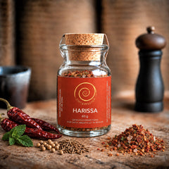 Eine Glas Harissa mit 60 g auf einem Olivenholzbrett 