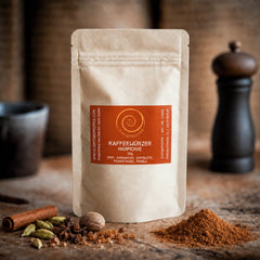 Eine 50 g Tüte Kaffeewürzer Harmonie auf einem Olivenholzbrett.