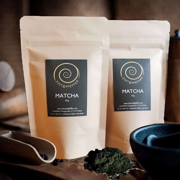 Zwei 80g Tüten Matcha auf einem Olivenholzbrett.