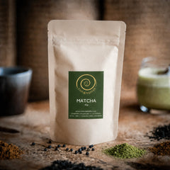Matche kaufen - eine 80g Tüte Matcha auf einem Olivenholzbrett