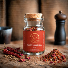 Ein Glas 60 g Rosen-Harissa auf einem Olivenholzbrett.