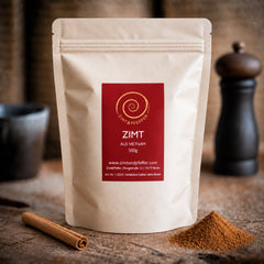 Eine Tüte Zimt aus Vietnam mit 500 g auf einem Olivenholbrett. Dieser Zimt ist aromatisch, würzig, süß und leicht scharf zugleich.