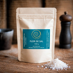 Flor de Sal aus Portugal von Zimt&amp;Pfeffer in der 1-kg-Zip-Tüte mit weißen Salzkristallen auf einem Holztisch