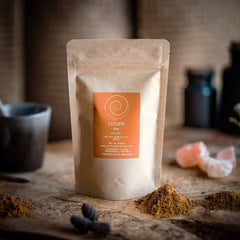 Eine Zip-Tüte aus Kraftpapier auf einem Olivenholzbrett. Bei dem Produkt handelt es sich um Lucuma, mit einer Füllmenge von 100g.