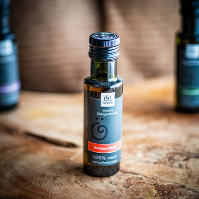 Eine Flasche 100ml Berliner Feuer - Bio-Würzöl auf einem Olivenholzbrett.