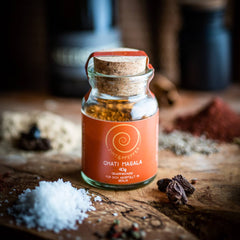 Eine 40g Glas Ghati Masala auf einem Olivenholzbrett.