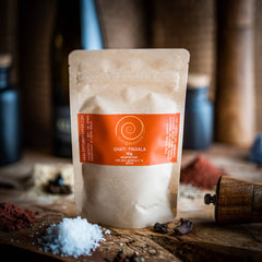 Eine 40g Tüte Ghati Masala auf einem Olivenholzbrett.
